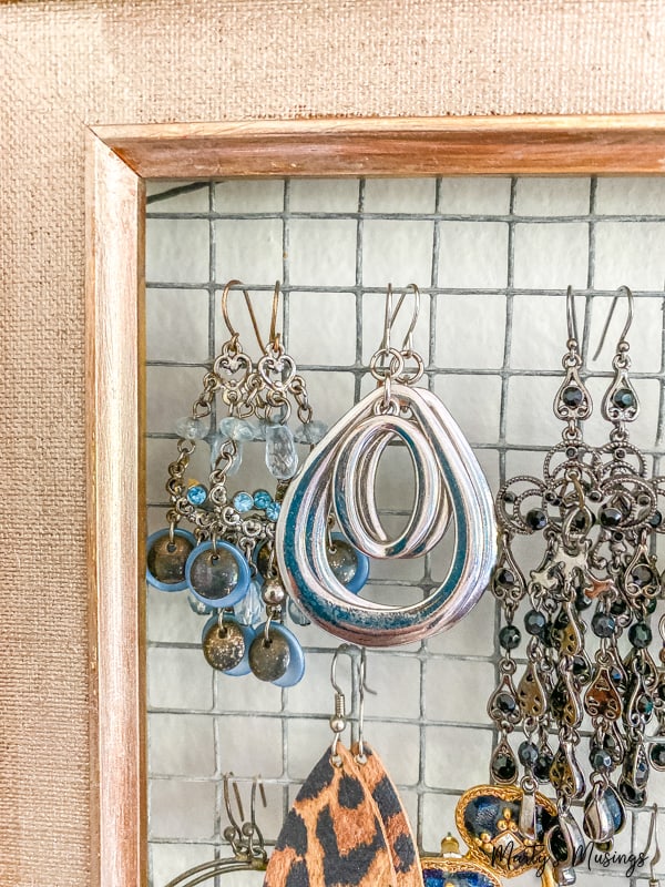 hoop earrings hanging on chicken wire in wooden frame